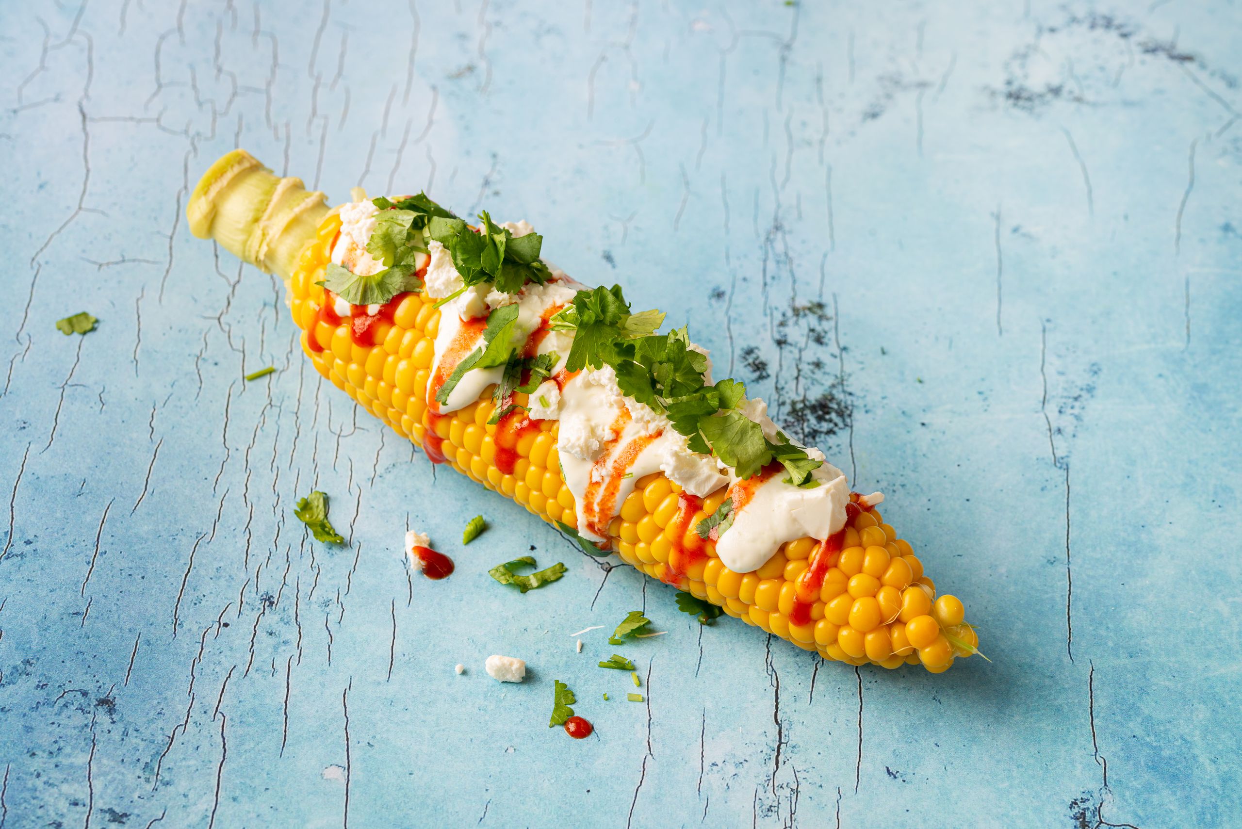 Mexikansk elote - kogt majskolbe dresset med lime dressing, fetaost, chilisauce og drysset med hakket korriander