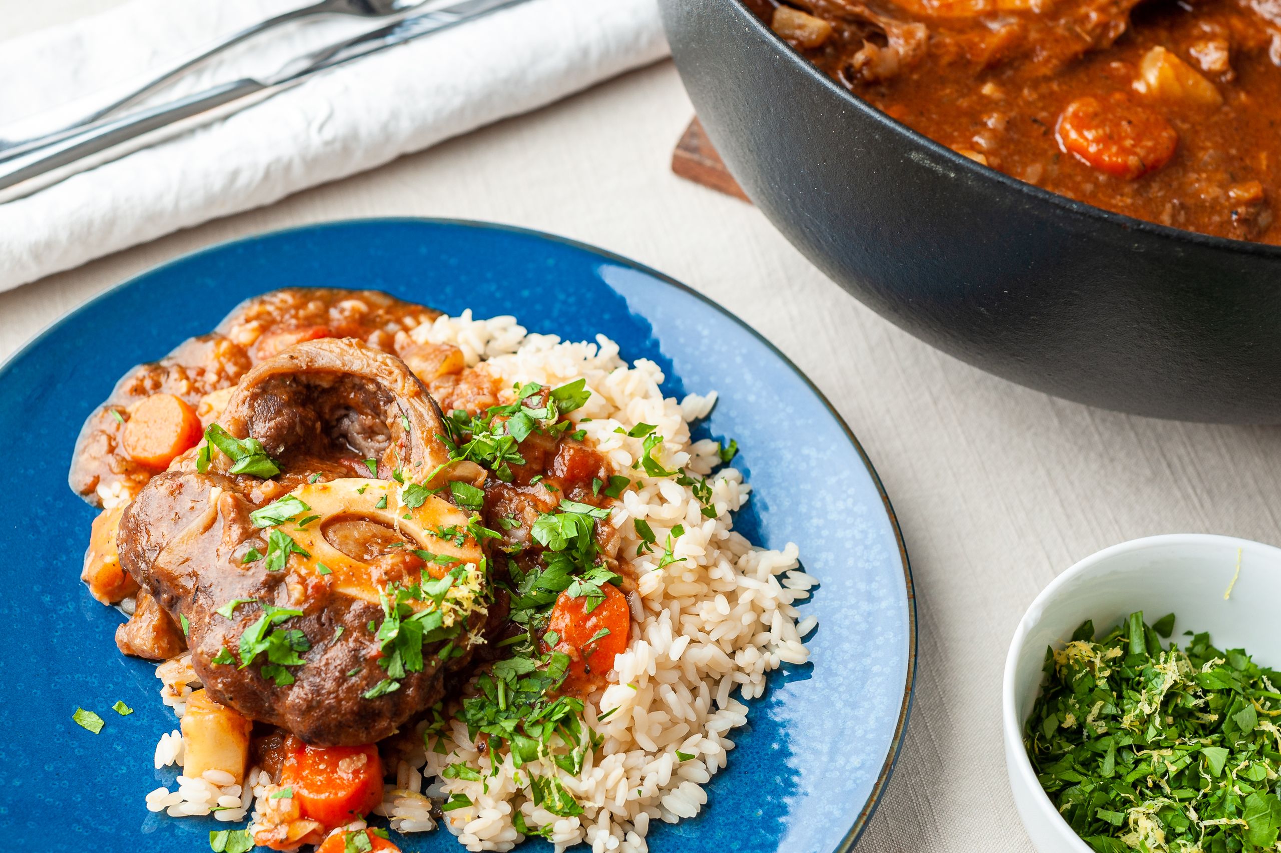 Ris og osse bucco serveret med et grønt drys af gremolata.